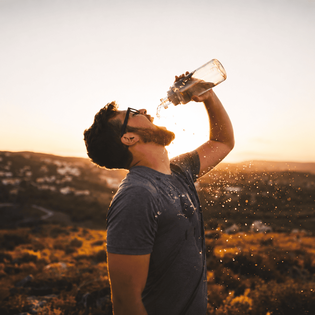 Hombre bebiendo agua al aire libre durante el atardecer